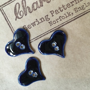 May include: Three dark blue ceramic heart-shaped buttons with two holes each.