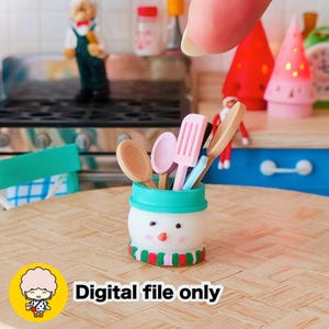 May include: A miniature snowman-shaped utensil holder with a teal rim and a red, green, and white striped scarf. The holder contains small wooden spoons, a spatula, and other kitchen tools. The text "Digital file only" is at the bottom.