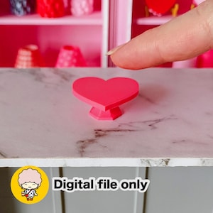 May include: A miniature, bright pink heart-shaped table with a pedestal base. The table sits on a surface with a marble pattern. The image includes the text "Digital file only".