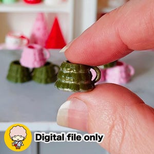 May include: A miniature green ceramic mug with a gold rim and handle is held between fingers. Other miniature mugs in pink and green are in the background. The image includes the text "Digital file only".