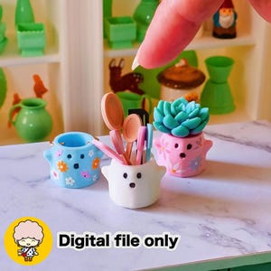 May include: Miniature ceramic pots in blue, white, and pink, decorated with flowers and a succulent. The white pot holds small utensils. The image includes the text "Digital file only".