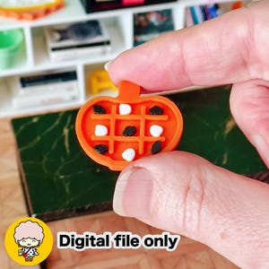 May include: An orange miniature pumpkin-shaped tray with a grid pattern, holding black and white candies. The text "Digital file only" is displayed in white on the bottom right. The tray is held in a person's hand.