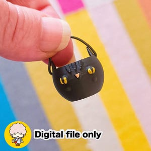 May include: A miniature black cat-shaped bag with gold-colored eyes and a nose, held by a person. The bag has a handle and is decorated with a cat face. The text "Digital file only" is displayed.