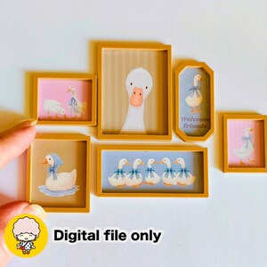May include: A collection of framed art prints featuring illustrations of geese. The frames are a warm yellow color, and the artwork includes geese with blue bows and the text "Welcome friends". The background colors vary, including pink, blue, and beige.