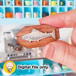 May include: A miniature wooden plaque featuring a silver-toned fish relief mounted on a brown, octagonal wood base. The item includes a yellow circular graphic in the corner with a cartoon character and the text Digital file only.