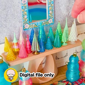 Puede incluir: Una colección de árboles en miniatura con forma de cono en varios colores, incluyendo amarillo, rosa, azul y verde, exhibidos en un estante claro. La imagen incluye un pequeño espejo con marco floral y el texto Digital file only.