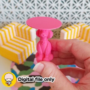 May include: A bright pink miniature table with a poodle-shaped base and a round tabletop. The table is held in a hand. The text "Digital file only" is visible in the lower left corner. The background includes a yellow and white striped couch.