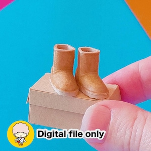 May include: Miniature tan-colored boots with white soles are displayed on a small cardboard box. The boots are made of a textured material. The image includes the text "Digital file only".