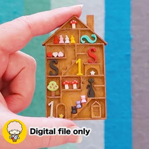 Könnte beinhalten: Ein Miniatur-Holzhaus mit mehreren Fächern, gefüllt mit bunten dekorativen Elementen. Enthält die Zahlen 1 und 2, den Buchstaben S, Herzen, Pilze, einen Baum, eine Katze und den Text "Digital file only".