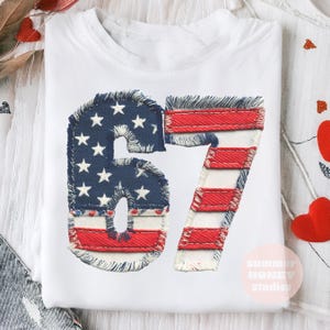 May include: White t-shirt with the number 67 appliquéd on the front. The number is designed to resemble the American flag, with blue fabric and white stars for the '6' and red and white stripes for the '7'.