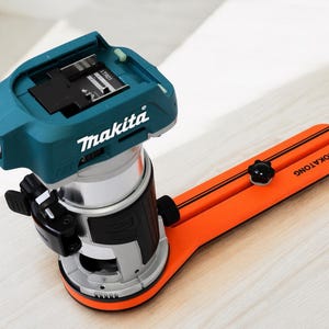 May include: A teal and silver Makita router with an orange Rokatong guide. The router has a black base and a teal top with the Makita logo. The orange guide has black stripes and the Rokatong logo.