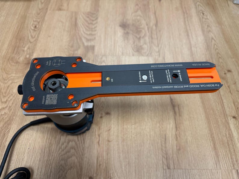 Puede incluir: Una plantilla de enrutador negra y naranja con el texto "cut clockwise" y "www.ROKATONG.COM". La plantilla est&aacute; unida a una base de enrutador. Tambi&eacute;n es visible el texto "For BOSH COIL, RIDGID and RYOBI compact routers".