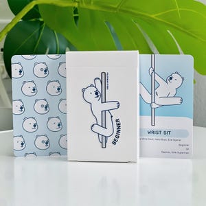 A beginner deck in a white box with a polar bear on a pole with the word "BEGINNER". The cards beside the box have polar bear illustrations. One of the card examples is a bear in a wrist sit trick.