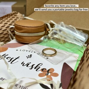 May include: A gold ring with a geometric design is displayed in a clear plastic bag. A small, round, tan jewelry case with a zipper is also visible. The text "favorite any item you love, we'll send you a portable jewelry bag for free" is in the background.