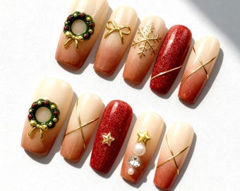 May include: A set of ten artificial nails with a Christmas theme. The nails feature a gradient design from beige to brown, adorned with gold bows, snowflakes, stars, and a wreath. Some nails have red glitter.