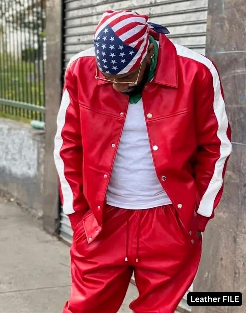 May include: Red leather jacket and matching pants with white stripes on the sleeves. The jacket has silver snap closures. The person is wearing a white undershirt and a bandana with the American flag design. The text "Leather FILE" is visible.