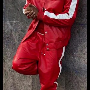 May include: Red leather jacket and matching pants with white stripes. The outfit includes a red and white bandana, gold-rimmed glasses, and white sneakers. The text "LEATHER FILE" is visible.