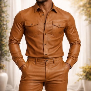 May include: A brown leather shirt and matching pants set. The shirt has two chest pockets and button closures. The pants have a classic five-pocket design. The outfit is a solid, warm brown color.