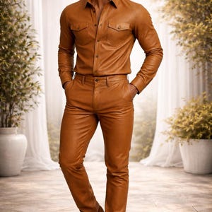 May include: A full-length shot of a person wearing a brown leather shirt and pants set. The shirt has two chest pockets and button closures. The pants are fitted. The person is also wearing brown suede boots.