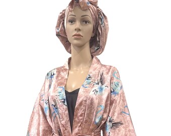 May include: A pink satin robe and matching bonnet set. The robe features a floral and bird pattern with blue accents. The robe has a belt and is knee-length. The bonnet is a ruffled style.