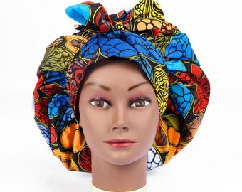 May include: A colorful bonnet with a vibrant African print, featuring a mix of blue, yellow, orange, and red patterns. The bonnet is tied with a bow on top, offering a stylish and protective hair covering.