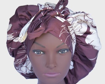 May include: A hair bonnet featuring a deep brown and cream floral pattern with a tie-top closure. The fabric has a smooth, satin-like finish and is gathered around the edges to create a voluminous, rounded shape that covers the head completely.