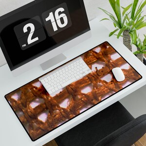 May include: A rectangular desk mat with a brown woven pattern. A white keyboard and mouse are on the mat, with a computer monitor displaying the time 2:16 PM in the background. The mat is on a white desk.