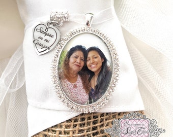 May include: A silver charm with a photo of two women and a heart-shaped charm with the inscription "Siempre en mi Corazon".