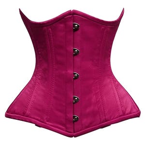 May include: A magenta corset with a structured silhouette. The garment features a series of silver-toned clasps down the center front and vertical seams for shaping. The corset has a curved neckline and a flared lower edge.