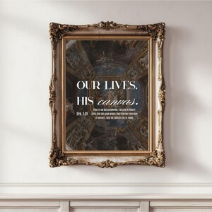 May include: A framed artwork with ornate gold detailing. The artwork features a detailed painting with a blue and brown color scheme. Text on the artwork reads "OUR LIVES. HIS canvas."
