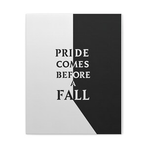 May include: A canvas print with a split design, half white and half black. The text "PRIDE COMES BEFORE A FALL" is vertically centered in bold, black letters, creating a striking contrast.