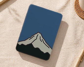 May include: A blue tablet case featuring a mountain illustration. The mountain design is in shades of gray and black, set against a solid blue background. The case is rectangular and appears to be made of a smooth material.