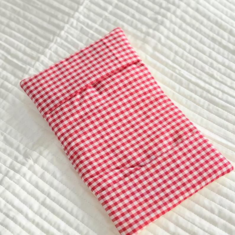 May include: A rectangular fabric pouch featuring a classic red and white gingham check pattern. The item has a folded top flap design and is constructed from a woven textile material with a consistent, repeating small-scale checkered print.