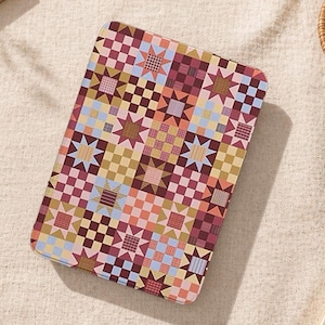 May include: A rectangular tablet case with a colorful patchwork design. The pattern features squares and star shapes in shades of pink, blue, yellow, and brown. The case is likely made of a durable material to protect the tablet.