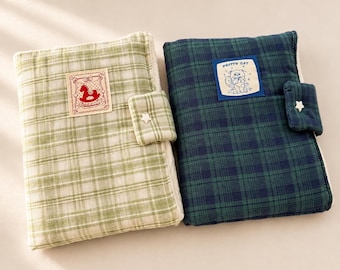 May include: Two rectangular fabric notebook covers with a plaid pattern. The left cover is light green and white with a patch featuring a red rocking horse. The right cover is dark green and navy blue with a patch labeled PRETTY CAT. Both have a star-shaped button closure.