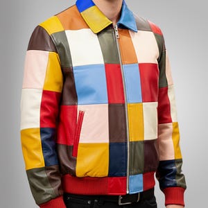 May include: A colorful patchwork leather jacket with a zip-up front, featuring a variety of square panels in shades of red, blue, yellow, pink, brown, and green. The jacket has a red ribbed hem and cuffs, and a blue and yellow collar.