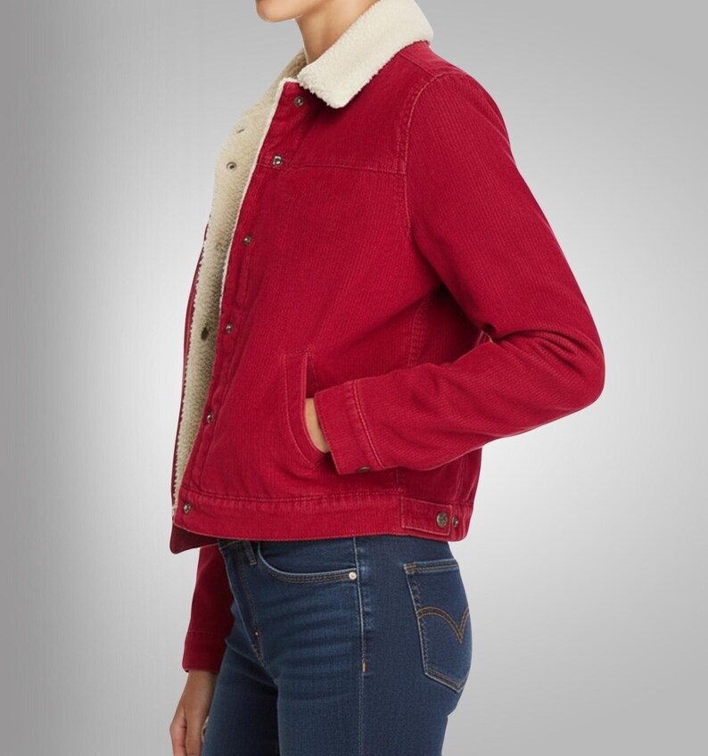 May include: A red corduroy jacket with a cream-colored, fuzzy lining and collar. The jacket has a button-up front, two front pockets, and long sleeves. The model is wearing blue jeans.