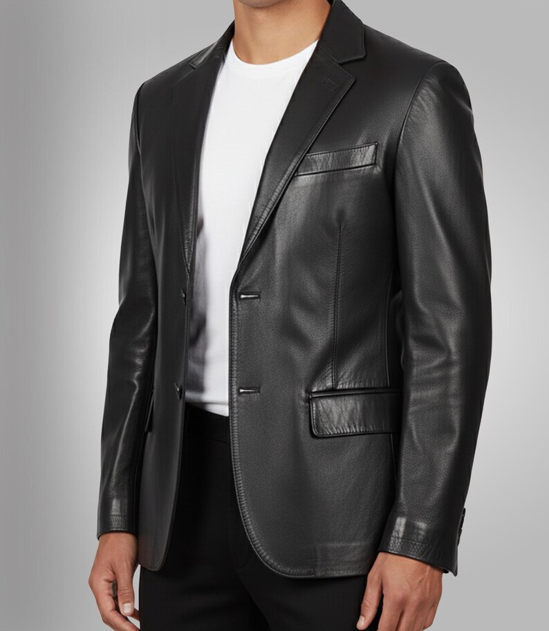 K&ouml;nnte beinhalten: Ein schwarzer Lederblazer mit Zwei-Knopf-Verschluss, Revers und Brusttasche. Der Blazer wird &uuml;ber einem wei&szlig;en T-Shirt getragen. Die Jacke hat eine klassische, taillierte Passform.