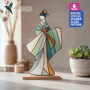Op de afbeelding: Een geisha figuur van glas in lood in blauw, groen, oranje en wit, gemonteerd op een houten voet. De figuur heeft een gedetailleerd ontwerp en wordt op een tafel getoond. De tekst "DIGITAL DOWNLOAD STAINED GLASS PATTERN" is ook aanwezig.