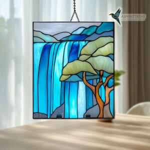 May include: Stained glass panel showing a waterfall and tree scene. The artwork uses blue, green, and orange hues, with a black border and a hanging chain. The rectangular panel is likely illuminated from behind, creating a vibrant display.