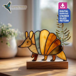 Könnte beinhalten: Eine Glasmalerei-Armadillo-Skulptur in Gelb-, Orange- und Blautönen, montiert auf einem Holzsockel. Das Kunstwerk weist ein detailliertes Design mit sichtbaren Linien und Texturen auf. Das Bild enthält auch den Text "DIGITAL DOWNLOAD STAINED GLASS PATTERN".