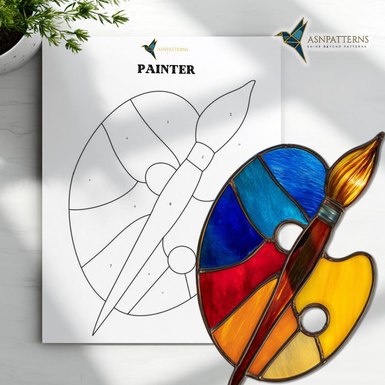 May include: A colorful stained glass palette and paintbrush are featured in this image. The palette is filled with vibrant hues of blue, red, orange, and yellow. The word "PAINTER" is printed on a white sheet of paper.