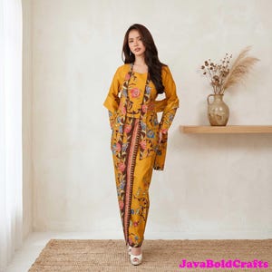 May include: Mustard yellow floral print outfit comprising a jacket, top, and skirt. The ensemble features a brown floral border and a matching floral pattern. The outfit is worn with white heels. The text "JavaBoldCrafts" is in the bottom right corner.