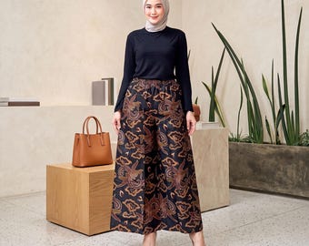 May include: A long-sleeved black crew-neck top paired with wide-leg trousers featuring a dark brown and black batik-style floral pattern. The trousers have an elasticated waistband and a loose, flowing silhouette that reaches the ankles.