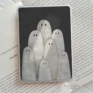 May include: A rectangular print featuring seven white ghost figures with simple black dot eyes arranged in a cluster against a dark gray background. Each ghost has a subtle, light-colored floral pattern on its surface, creating a layered effect.