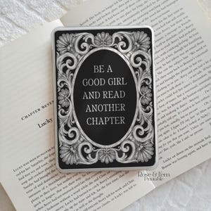 May include: Black and white rectangular sticker with the text "BE A GOOD GIRL AND READ ANOTHER CHAPTER" in a decorative oval frame. The sticker has an ornate floral border.