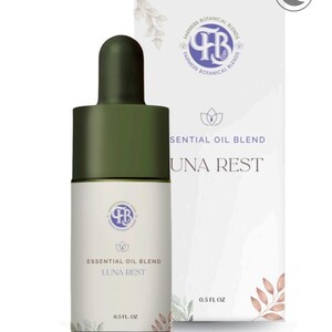 Puede incluir: Una botella blanca de mezcla de aceites esenciales con un cuentagotas verde y una caja a juego. La botella y la caja presentan el texto "LUNA REST" y "ESSENTIAL OIL BLEND". La caja también muestra el logotipo de Farmers Botanical Blends y un icono de luna creciente.