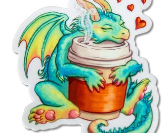 May include: A sticker featuring a teal dragon with yellow and orange accents, hugging a coffee cup. The dragon has closed eyes and steam rising from the cup. Small red hearts float above the dragon's head.