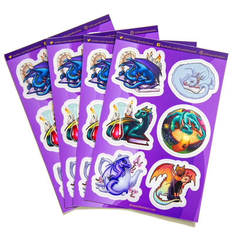 Peut inclure: Quatre feuilles d'autocollants repr&eacute;sentant diverses illustrations de dragons dans diff&eacute;rentes poses et situations. Les autocollants sont imprim&eacute;s sur un fond violet avec des bordures blanches. Les autocollants repr&eacute;sentent des dragons lisant des livres, dormant, volant et tenant des tasses &agrave; th&eacute;. Le texte "thespindlesisters.com" est imprim&eacute; en bas des feuilles.