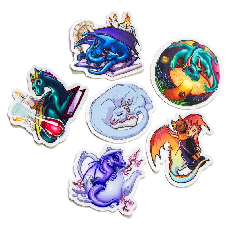 Peut inclure: Ensemble de sept autocollants de dragons color&eacute;s. Chaque autocollant pr&eacute;sente un design de dragon diff&eacute;rent, notamment un dragon lisant un livre, un dragon dormant, un dragon dans une th&eacute;i&egrave;re et un dragon avec un chat.
